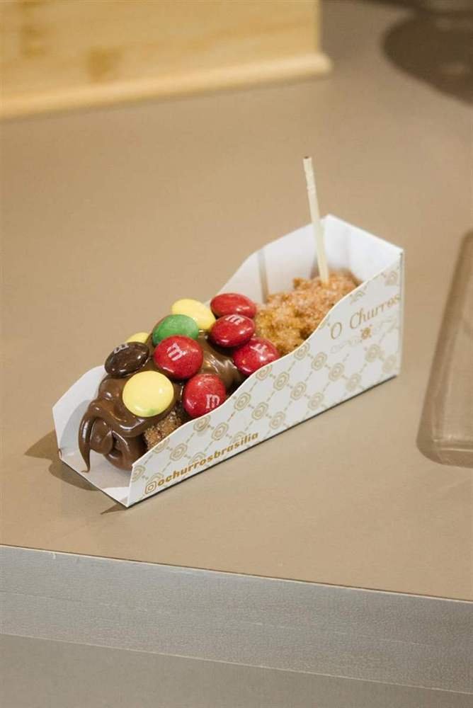 Churros gourmet com cobertura de chocolate e confeitos coloridos