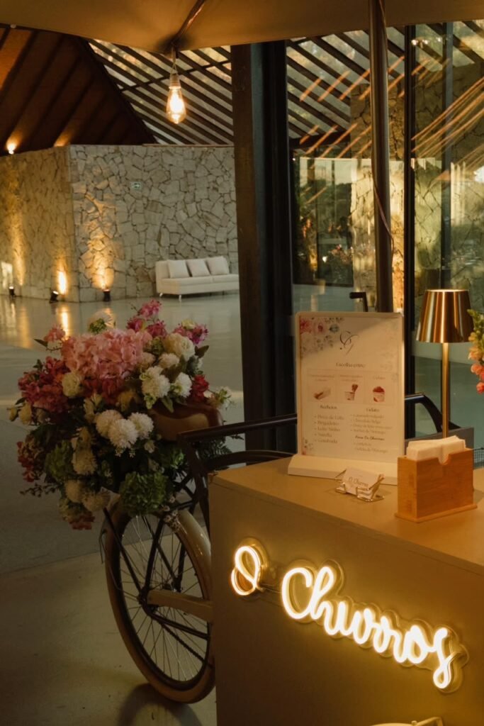 Carrinho de churros com bicicleta decorada com flores e neon O Churros em casamento