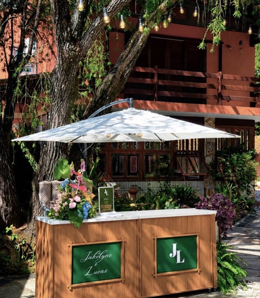 Carrinho de churros com placas verdes personalizadas com o nome dos noivos e arranjo de flores