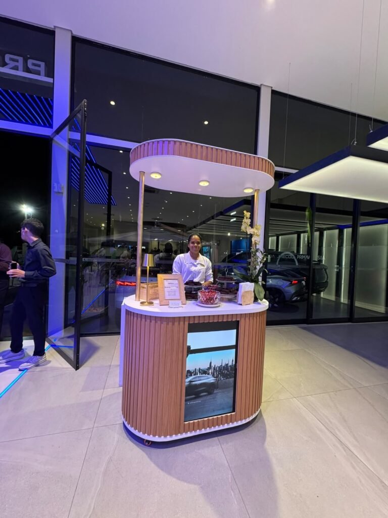 Carrinho gourmet com tela de TV exibindo vídeo da marca em evento corporativo