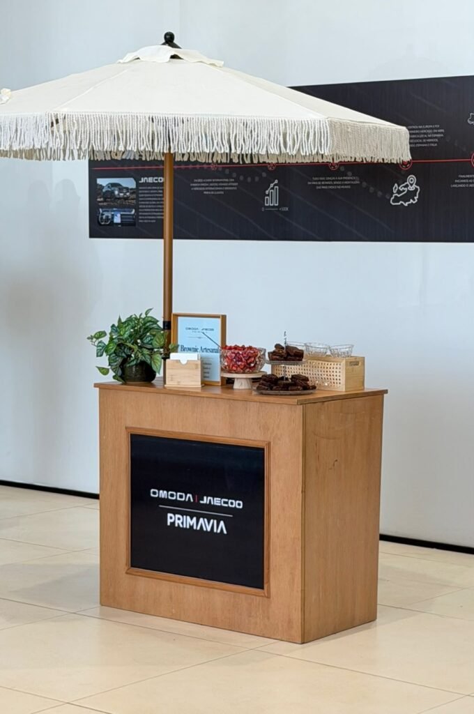 Mesa de brownie artesanal com guarda-sol em evento OMODA JAECOO Primavia