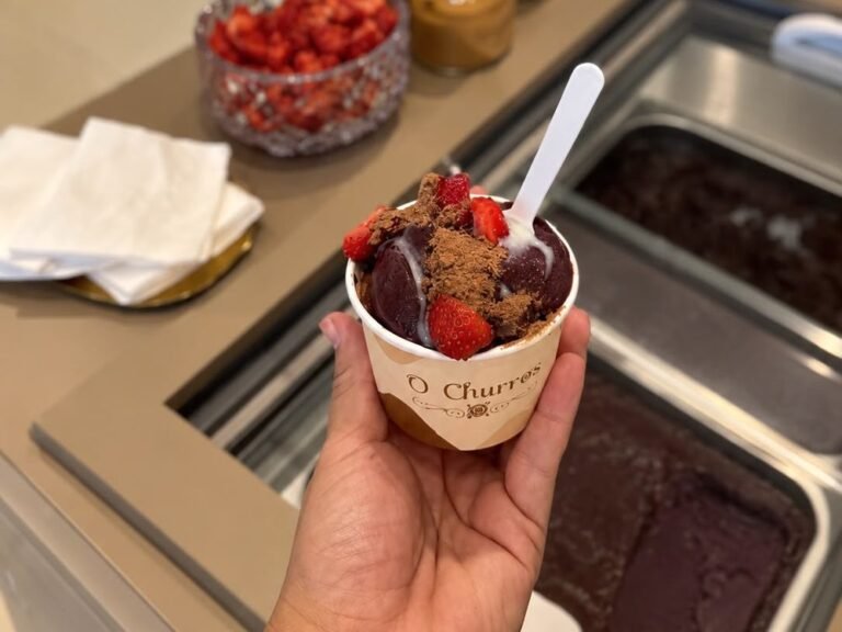 Açaí servido em copo do Ateliê O Churros com morangos e acompanhamentos